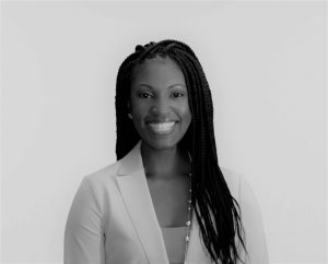 Portrait of Dr. Celeste Green. Dr. Green is a black woman with long black braids. She is wearing a tan blouse, white suit coat, and gold necklace and smiling at the camera.
