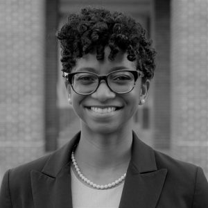 Portrait of Dr. Nikea Pittman. Dr. Pittman is a Black woman with short curly hair. She is wearing glasses, a dark suit jacket and pearls and smiling at the camera.
