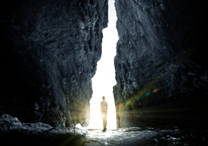 Person standing in the light between towering rocks